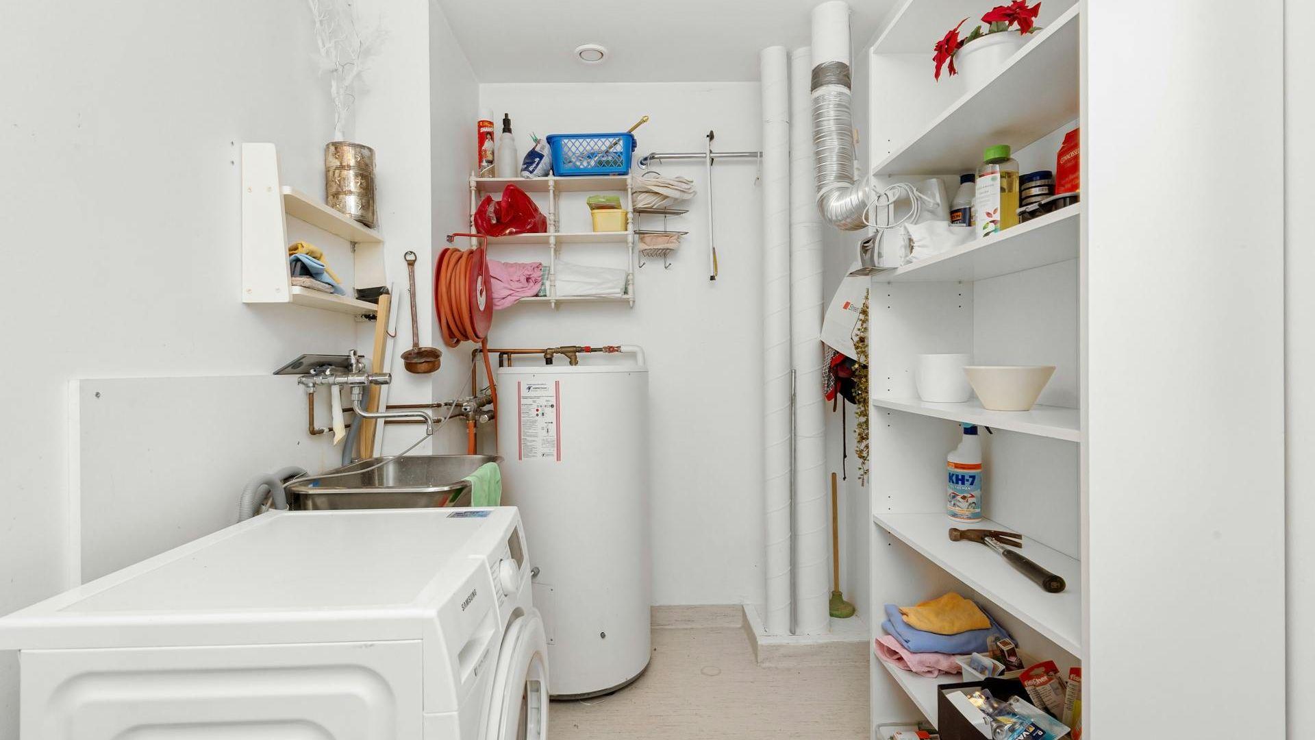 Slightly cluttered laundry room with a water heater at the far end