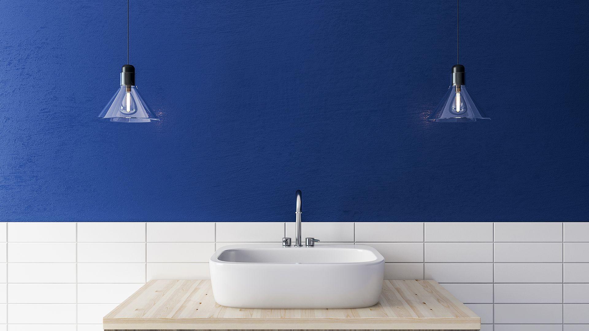 Clean white sink in front of a wall that's half subway tile and half blue